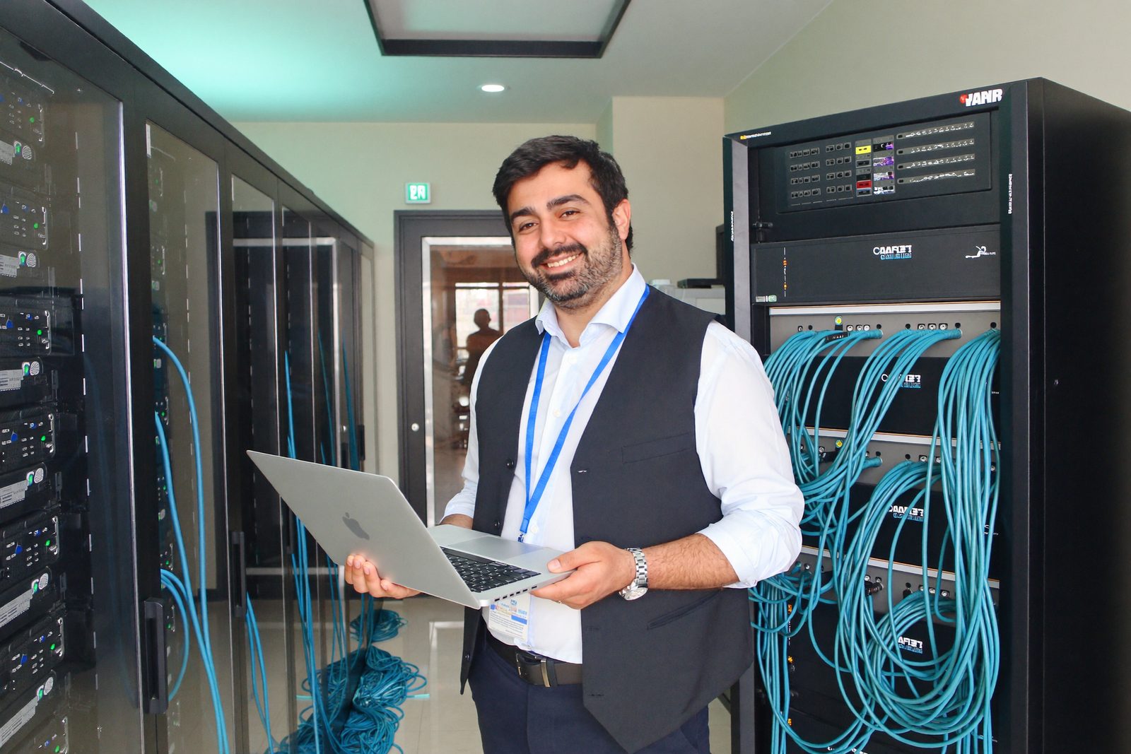 A smiling network engineer in front of tidy server racks